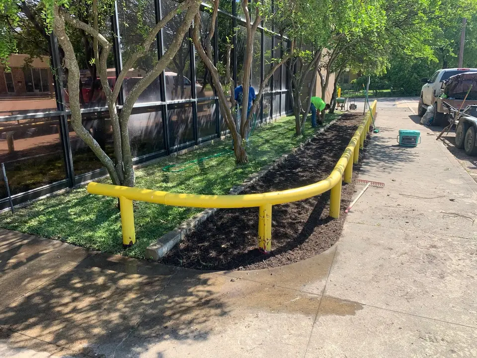 Crew installing a planting bed and new grass beside a commercial building