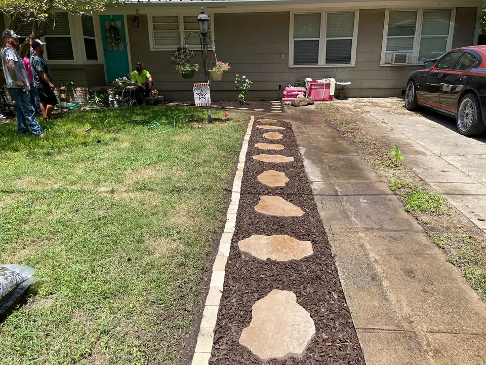 Stepping-stone walkway with brown mulch and edging in a front yard